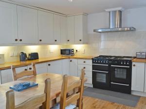 a kitchen with a wooden table and a stove at Havannah Cottage in Alnham