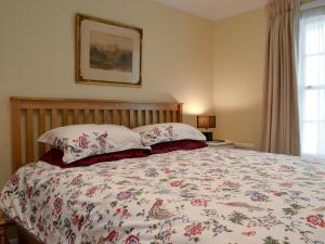 a bedroom with a large bed with a floral bedspread at The Old Rectory Lodge in Yaxham