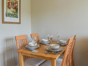 een houten tafel met stoelen en wijnglazen erop bij Melody in Bowness-on-Windermere