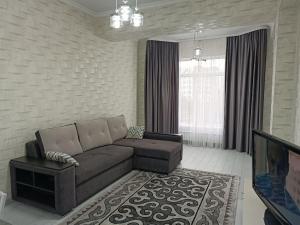 ein Wohnzimmer mit einem Sofa und einem TV in der Unterkunft Комфортная двухкомнатная квартира in Bischkek