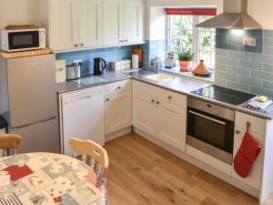 a kitchen with white cabinets and a table and a microwave at Keldholme Cottage 1 - Uk10992 in Kirkbymoorside