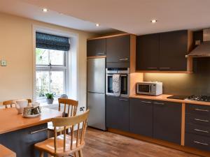 a kitchen with black cabinets and a table with chairs at Chapel House in Bardon Mill