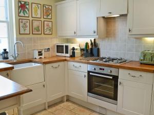a kitchen with white cabinets and a stove top oven at Durdrich Cottage in St Margarets at Cliff