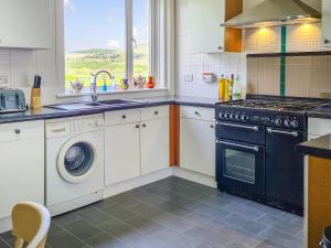 cocina con fogones y lavavajillas en Craik Forestry Cottage, en Teviothead