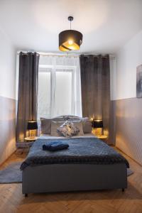 a bedroom with a bed with a blue comforter and a window at ClickTheFlat Wilcza 35 City Center Apart Rooms in Warsaw
