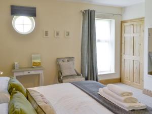 a bedroom with a bed and a chair and a window at Lapwing Cottage in Longframlington