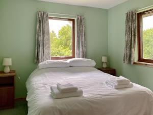 uma cama branca num quarto com uma janela em Kintulloch em Insh