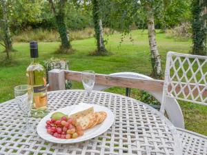 una mesa con un plato de comida y una botella de vino en The Squirrels strelley Barn en Woodham Mortimer