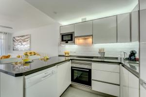a white kitchen with white cabinets and appliances at SVA&YA Sunflower In Playa La Arena in Puerto de Santiago