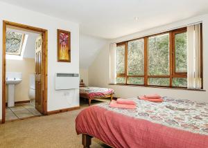 a bedroom with a bed with red sheets and windows at Exmoor Gate Lodges in Chipstable