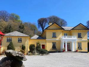 une grande maison jaune avec une grande allée. dans l'établissement Rosecraddoc Manor - Hayloft, à Saint Cleer