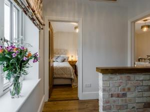 Pokój z łóżkiem i wazonem kwiatów na ladzie w obiekcie Wisteria House w mieście Henstead