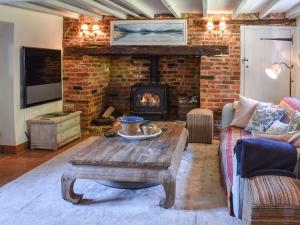 a living room with a table and a fireplace at Chapel Cottage, in Holmbury Saint Mary