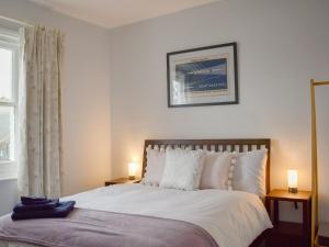 a bedroom with a bed with two lamps and a window at Guillemots in Littlehampton