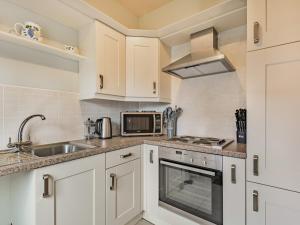 a kitchen with white cabinets and a sink and a microwave at The Potting Shed - Uk36120 in Horsington