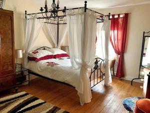 a bedroom with a canopy bed with white curtains at Ashley Cottage in Colsterworth