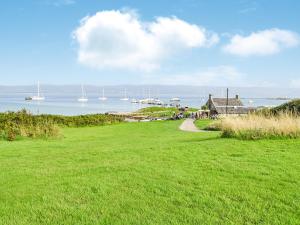 un campo de césped con una casa y barcos en el agua en The Stable - Uk33400 en Isle of Gigha