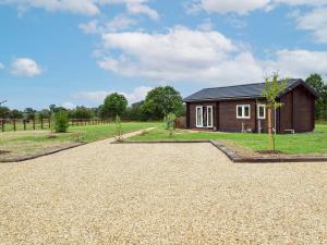 a house in a field with a gravel driveway at Pheasant Lodge - Uk33402 in Hungerton