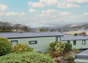 a green building with mountains in the background at Tan-y-fron Holiday Park in Dolgellau