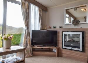 a living room with a flat screen tv and a window at Tan-y-fron Holiday Park in Dolgellau