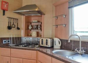 uma cozinha com um lavatório e um fogão forno superior em Tan-y-fron Holiday Park em Dolgellau