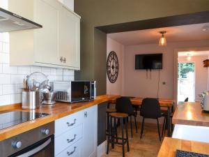 a kitchen with white cabinets and a table with a laptop at Loyal Cerise in Cawood
