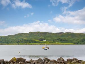 ein Boot auf einem See mit Hügeln im Hintergrund in der Unterkunft Puffin - Kerrera in Lerags