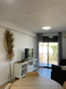 a living room with a flat screen tv and a table at Acogedor apartamento Vallparadís con parking in Terrassa