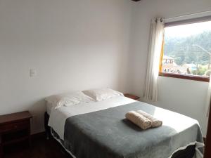 a bedroom with a large bed with a window at Chalé refúgio in Monte Verde