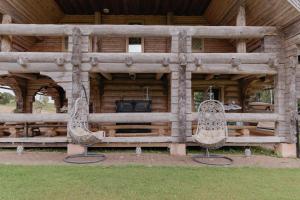 uma cabana de madeira com duas cadeiras à frente em Viesu nams “Kalna Raskumi” em Vecpiebalga
