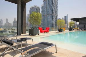 - une grande piscine avec des chaises et des tables dans un bâtiment dans l'établissement WORLD CLASS 3BR in the HEART of DUBAI, à Dubaï