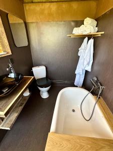 a bathroom with a tub and a toilet and a sink at Krusmølle Glamping in Aabenraa