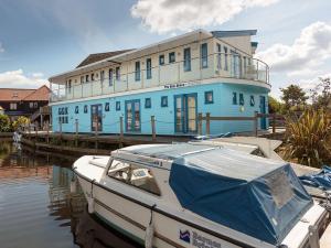 una barca è ormeggiata di fronte a un edificio blu di Riversedge - Cvl a Wroxham