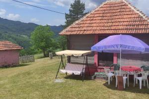 une maison avec des chaises et des parasols devant elle dans l'établissement Šeherezada, à Kosjeric