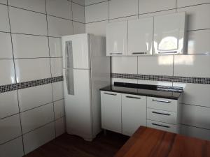 a kitchen with white cabinets and a refrigerator at Chalé refúgio in Monte Verde