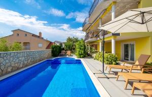 a swimming pool with chairs and an umbrella next to a house at Apartment MARO in Senj