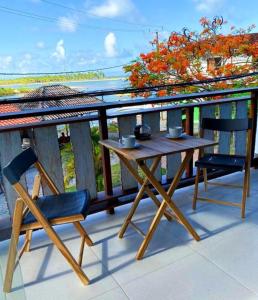 a wooden table and two chairs on a balcony at Pousada Atracadouro Boipeba in Cayru