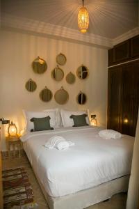 um quarto com uma grande cama branca com espelhos na parede em Riad Sabria em Marrakech