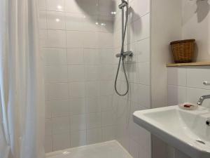 La salle de bains blanche est pourvue d'une douche et d'un lavabo. dans l'établissement Suite Bergame, à Caluire-et-Cuire