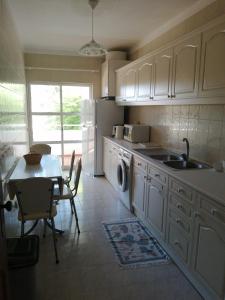a kitchen with white cabinets and a table and a sink at T2 Maralvor in Alvor