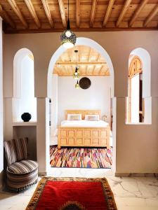 a bedroom with a bed and a chair and a rug at Riad Al Manara in Essaouira