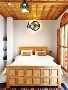 a bedroom with a large bed with a wooden headboard at Riad Al Manara in Essaouira
