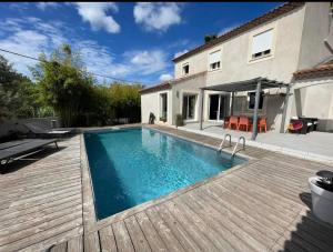 a swimming pool with a wooden deck and a house at Chambre à Bouzigues dans villa individuelle in Bouzigues