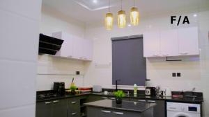 una cucina con armadi bianchi e piano di lavoro nero di Favourite Luxury 2 Bedroom Apartment a Ikeja