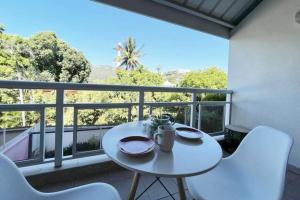 d'une table et de chaises blanches sur un balcon. dans l'établissement HEIPOE LODGE - 6 min airport, Wifi, AC & Parking, à Papeete