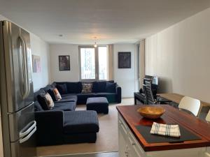 Spacious Flat in Manor House, London في لندن: غرفة معيشة مع أريكة زرقاء ومطبخ