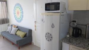 eine Küche mit einem Sofa und einer Mikrowelle auf einem Kühlschrank in der Unterkunft Alquiler Temporario Shanti in Trelew