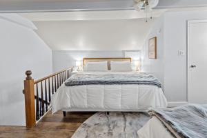 a white bedroom with a bed and a staircase at The Original Custom House! in St. Charles