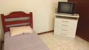 1 dormitorio con cama y vestidor con TV en Paraiso de Itaipu, en Itaipú