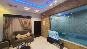 salon z kanapą i dużym telewizorem w obiekcie شاليهات قمرا w mieście Qarār